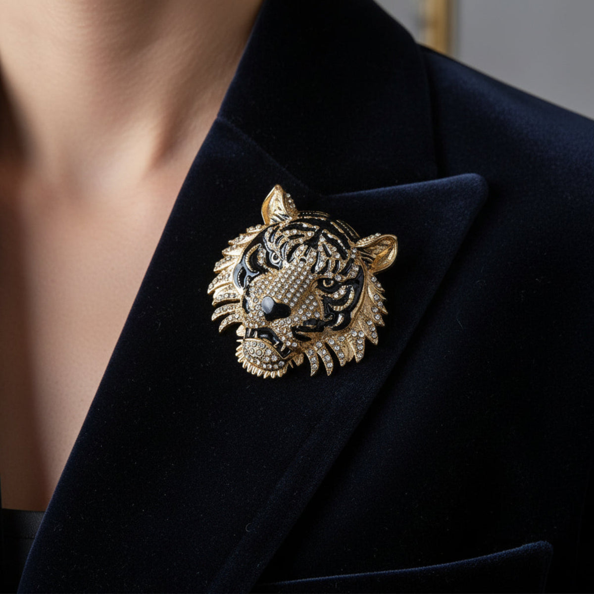 A tiger head brooch featuring a black and gold enamel design, detailed with clear rhinestones on its face, eyes, and mane, set against a plain white background.