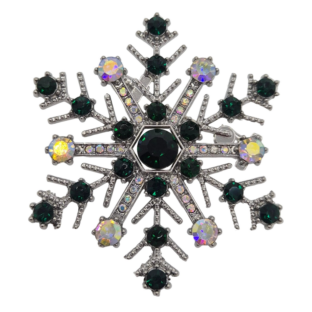 A snowflake-shaped brooch featuring a central black round crystal surrounded by smaller dark green and iridescent faceted crystals, set in a silver-toned metal.