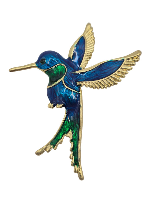 A hummingbird brooch featuring vibrant blue and green enamel with gold-tone metal outlines and wings, set against a plain white background.
