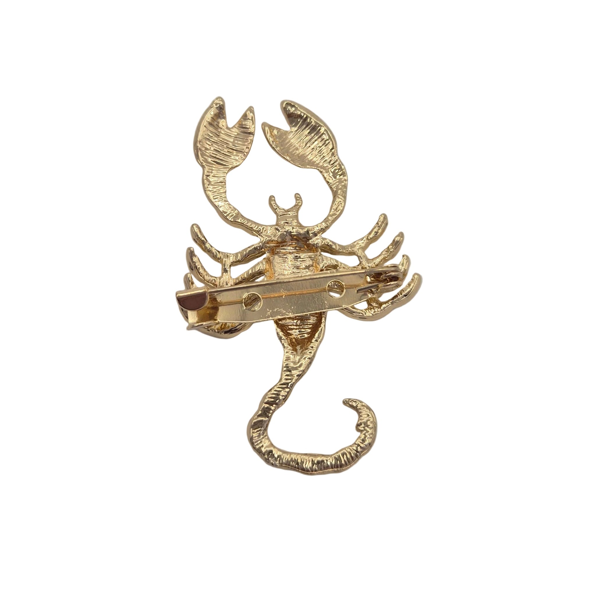 A gold metal scorpion brooch showing the pin mechanism on the underside, photographed on a plain white background.