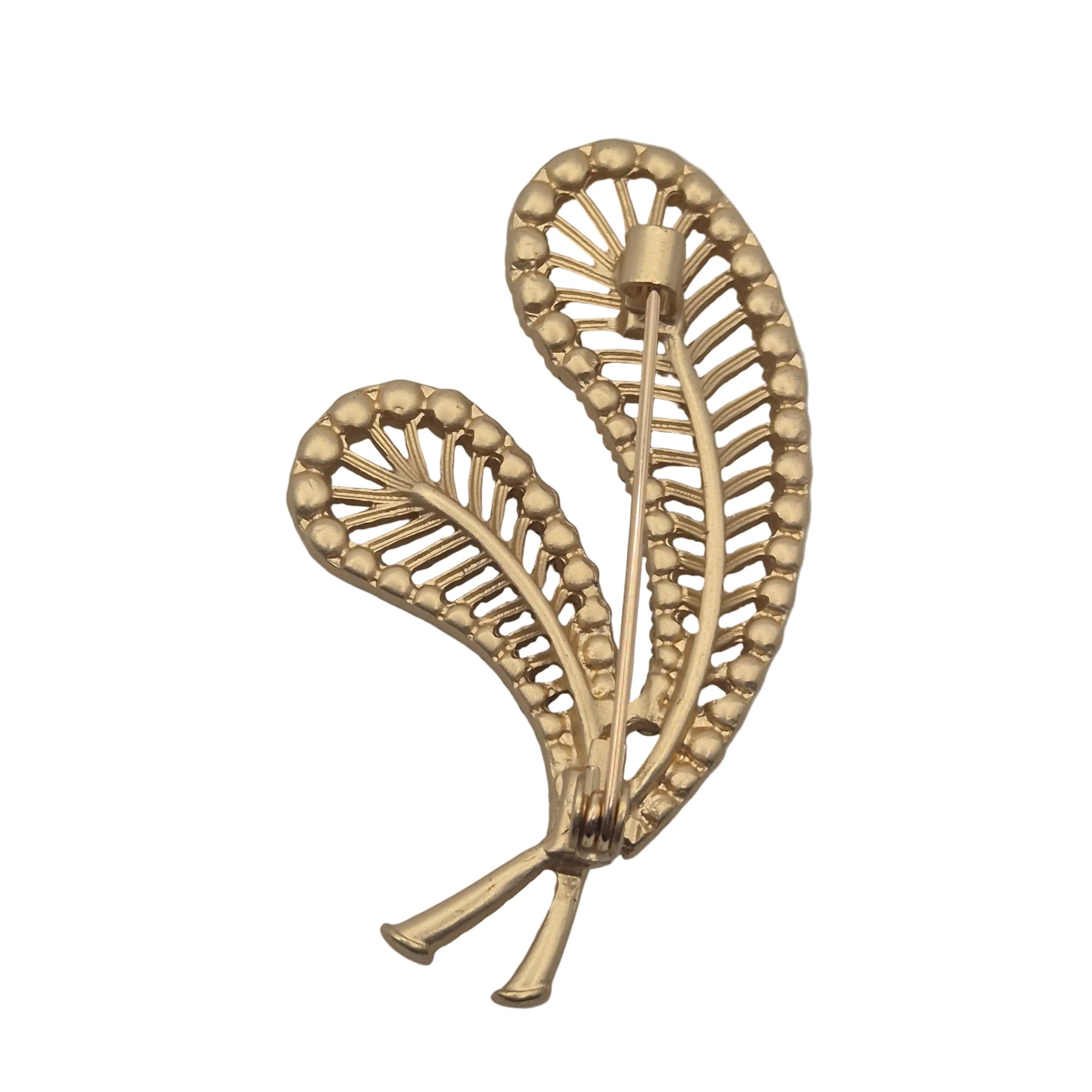 A gold-toned metal brooch shaped like two overlapping feathers with beaded edges and a pin fastener visible at the top, shown on a plain white background.