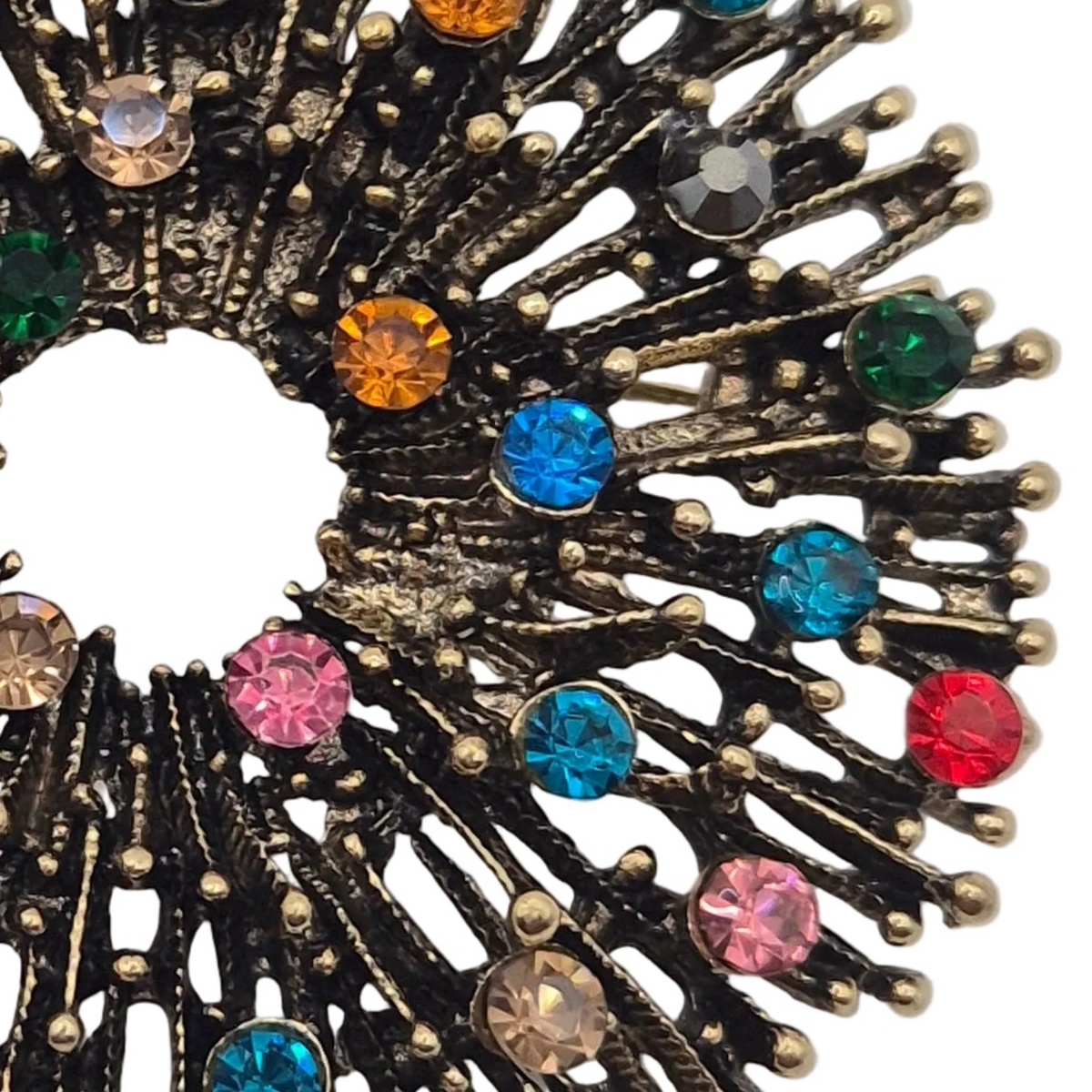 A circular firework brooch featuring a antique gold metal base with multiple radiating spikes adorned with small, colourful rhinestones in pink, blue, orange, green, and purple, shown against a plain white background.