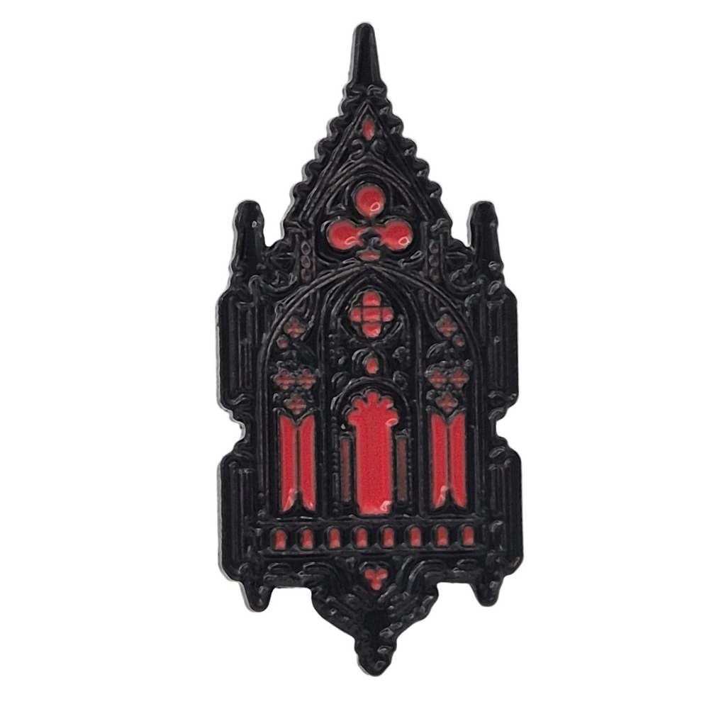 A gothic cathedral shaped enamel pin with a black metal outline and vibrant red enamel details, shown against a plain white background.