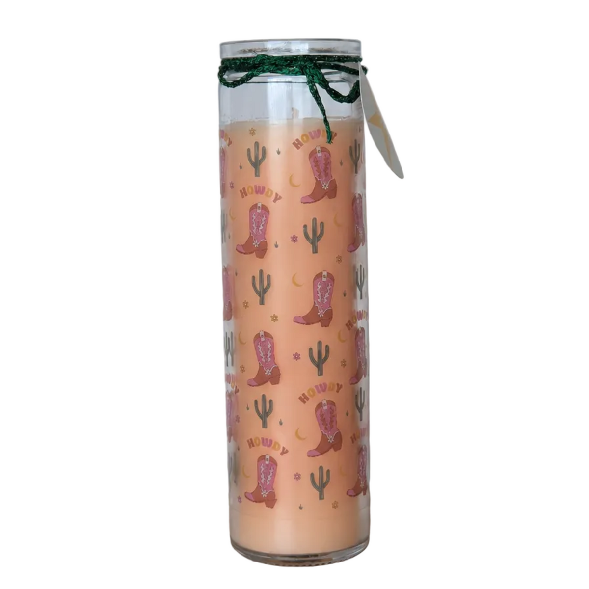 A tall glass jar candle with a peach-coloured wax body, decorated with a repeating pattern of pink cowboy boots, green cacti, and the word 'HOWDY' in yellow. The jar is tied with a dark green glittery ribbon and has a white paper tag attached.