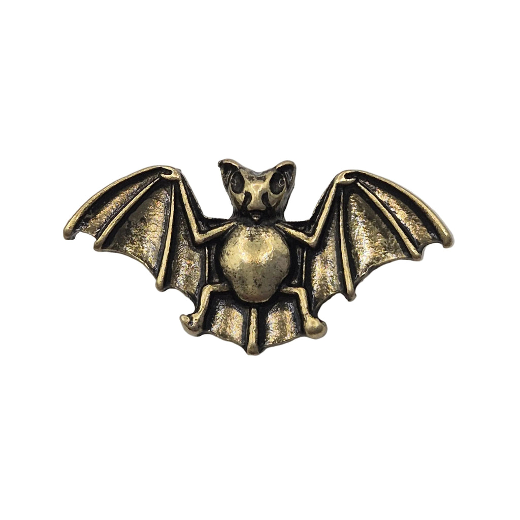 An antique gold tone metal bat pin brooch with spread wings, shown on a plain white background.