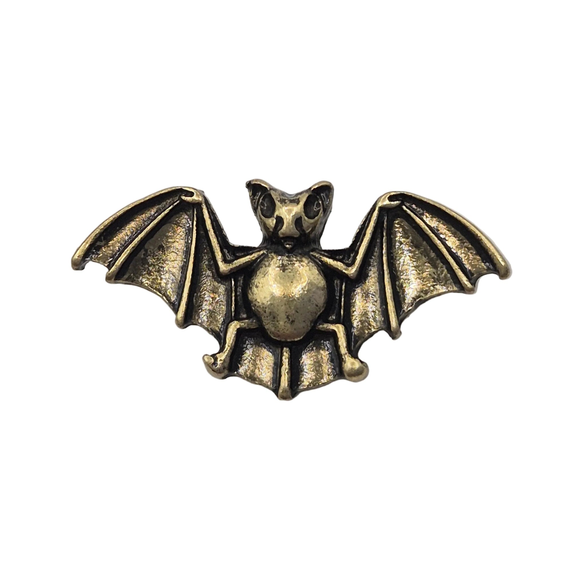 An antique gold tone metal bat pin brooch with spread wings, shown on a plain white background.