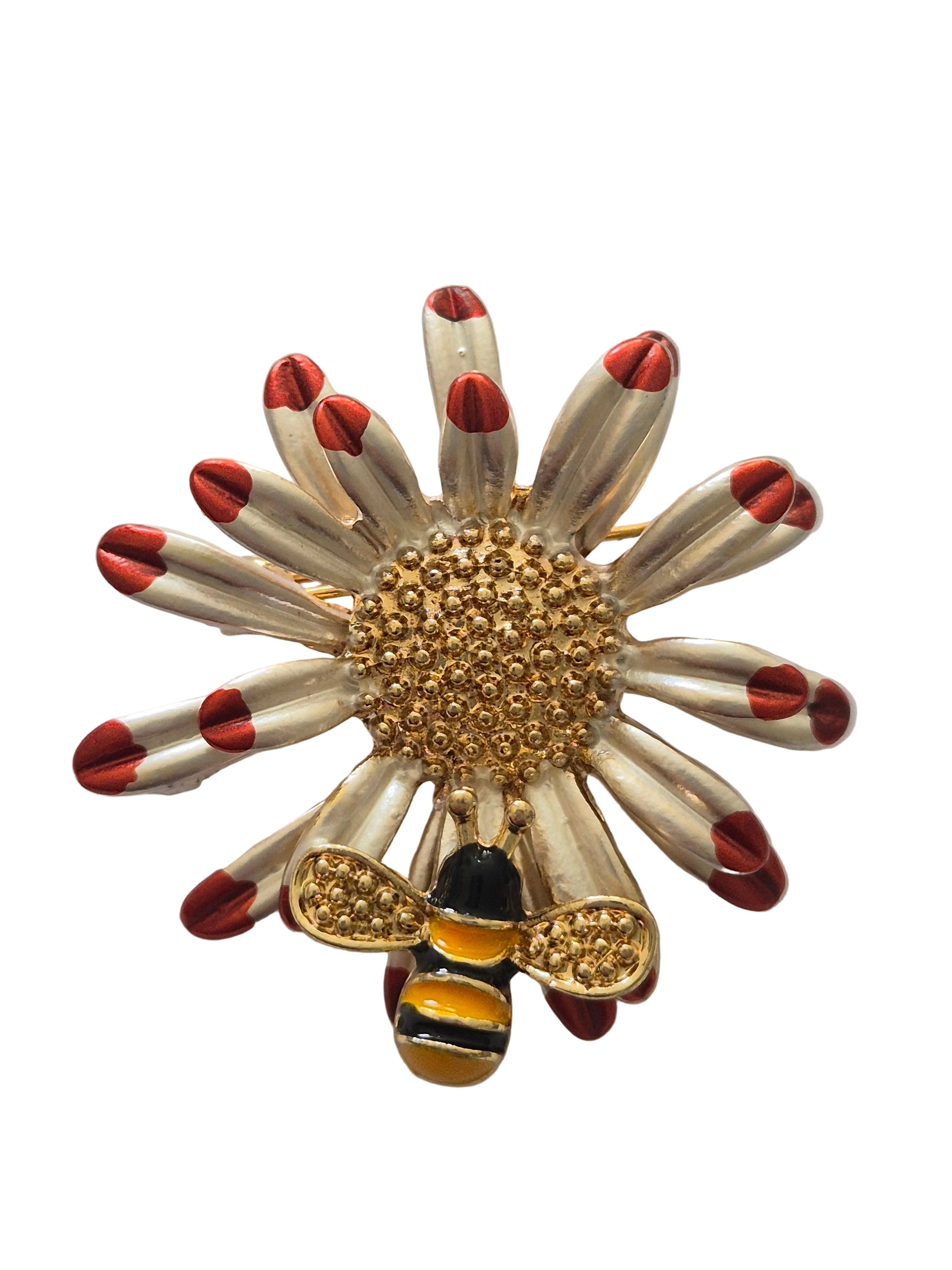 Decorative brooch with gold center, red accents, and bee design on a white background