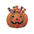 A Halloween-themed enamel pin shaped like a jack-o'-lantern pumpkin with candy overflowing from the top, shown on a plain white background.
