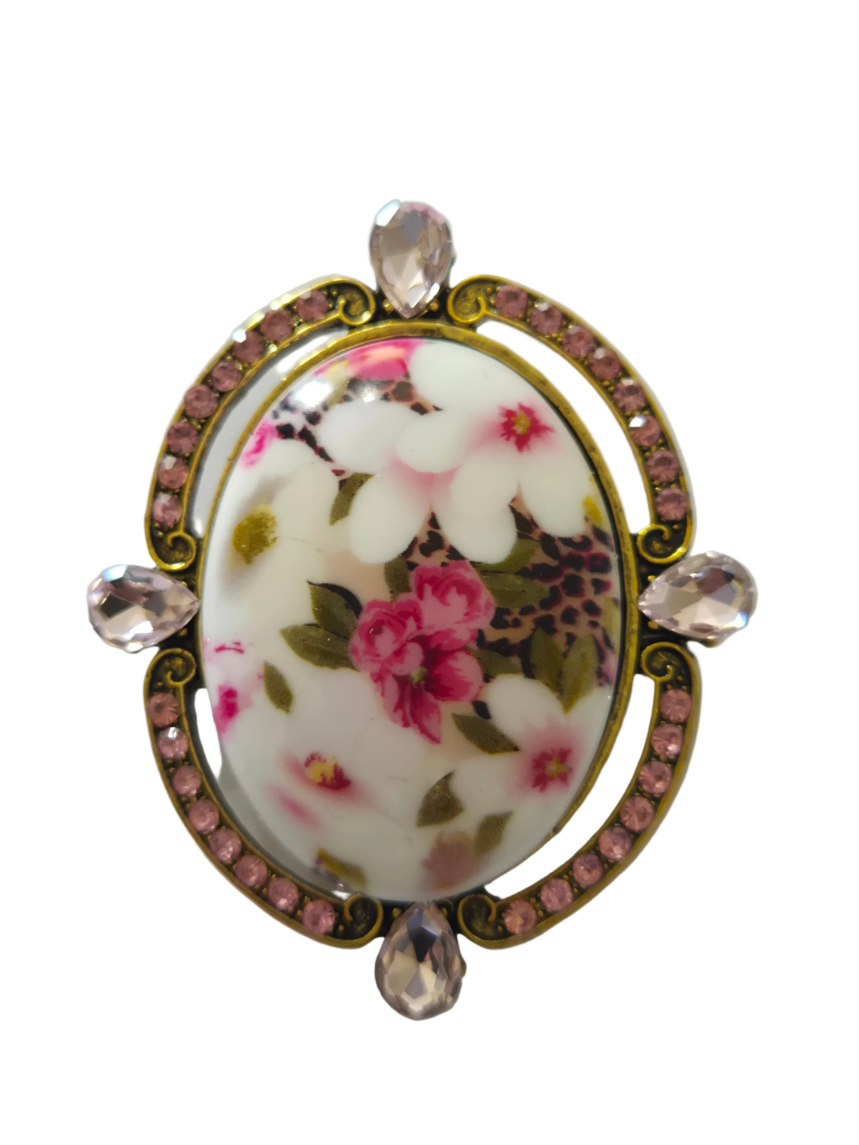 Decorative brooch with floral design and rhinestones on a light gray background