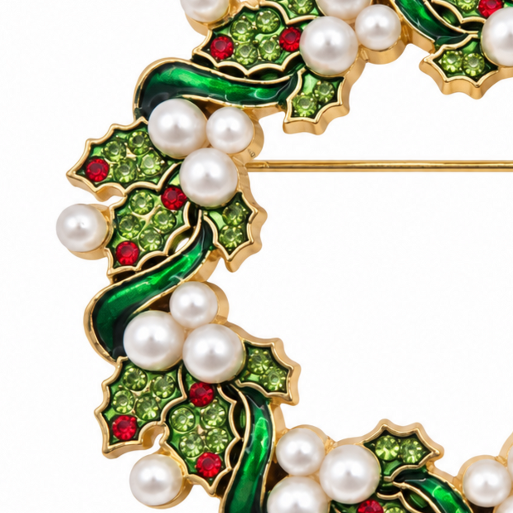 A close-up of a gold-tone brooch featuring green enamel holly leaves, white faux pearls, and small red crystal accents on a white background.