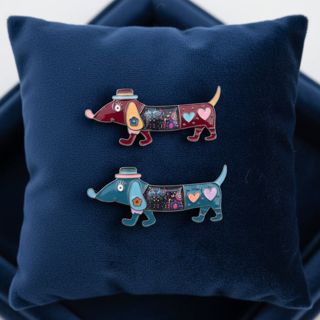 Two colorful enamel brooches shaped like dachshund dogs, one in red and the other in blue, both decorated with hearts, stars, and small hats, shown on blue velvet cushion background.