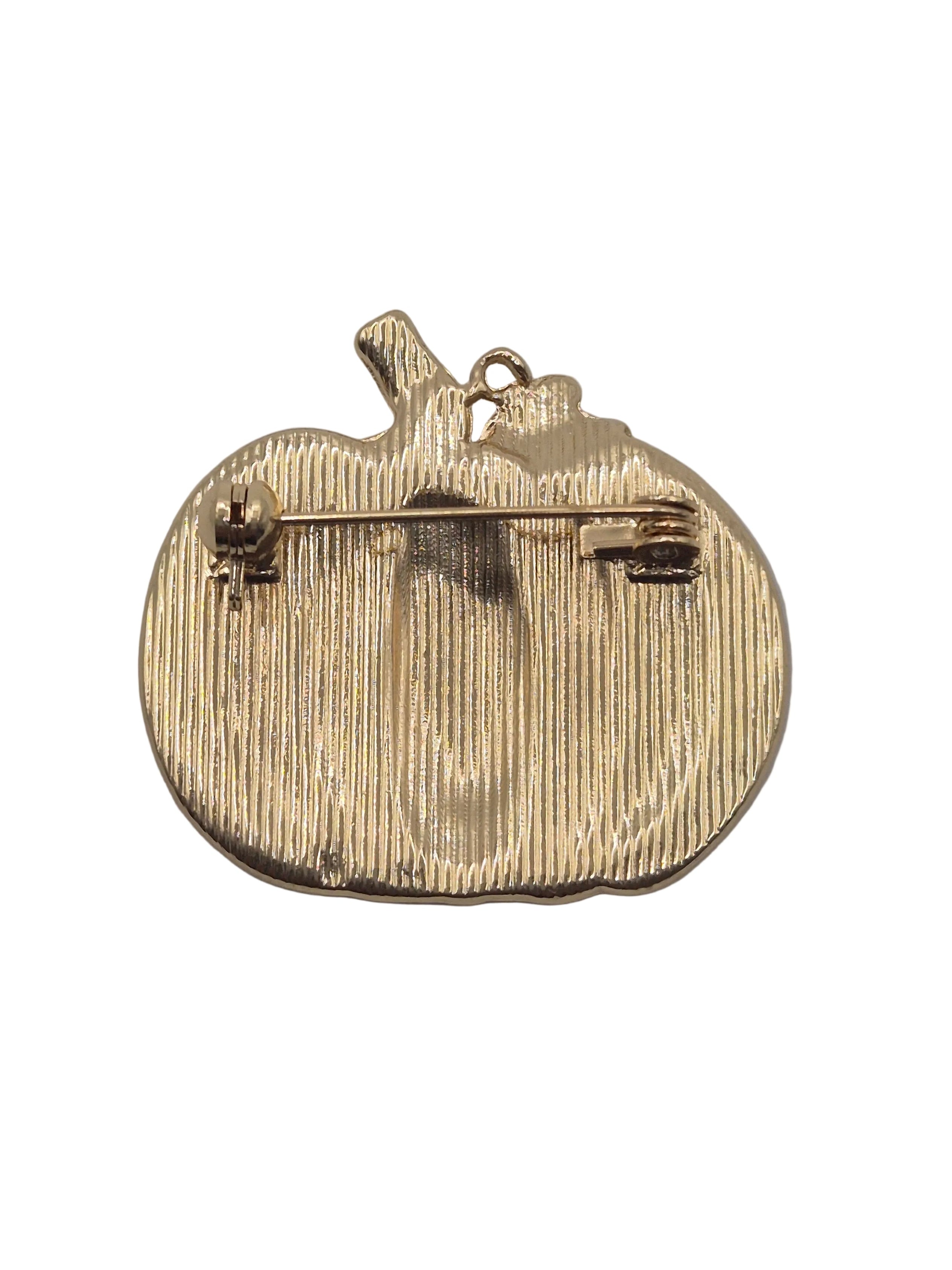 A gold pumpkin-shaped brooch showing the back side with a safety pin clasp, on a plain white background.