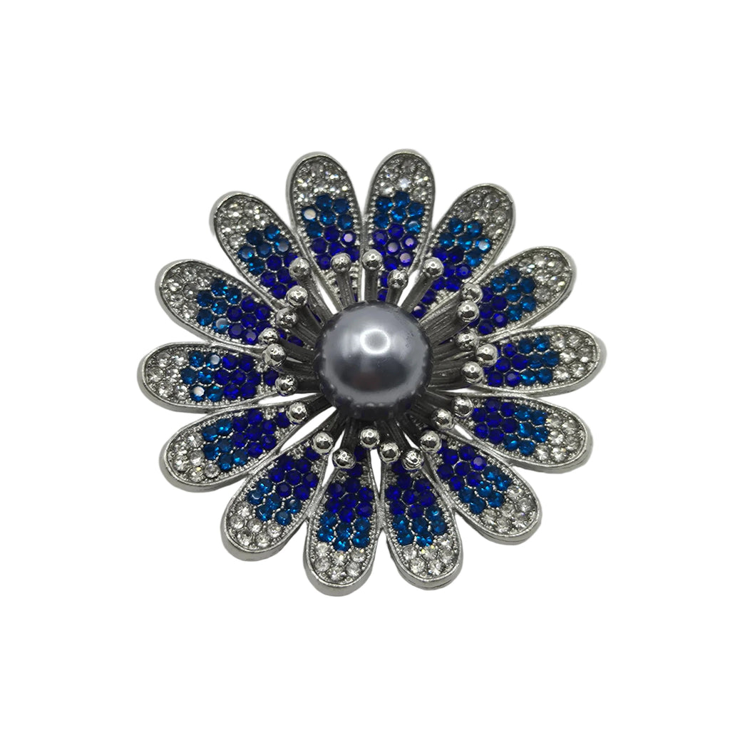 A flower-shaped brooch featuring a central gray pearl surrounded by silver-toned metal petals, with blue and clear rhinestones in each petal, set against a plain white background.
