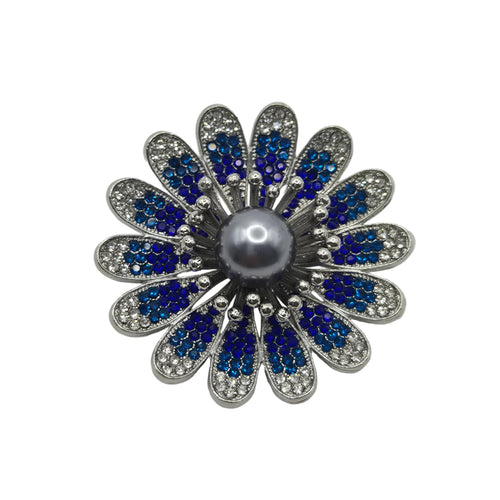 A flower-shaped brooch featuring a central gray pearl surrounded by silver-toned metal petals, with blue and clear rhinestones in each petal, set against a plain white background.