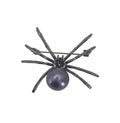 A spider-shaped brooch featuring a dark gray metallic body with a prominent oval purple pearl, photographed on a plain light gray background.