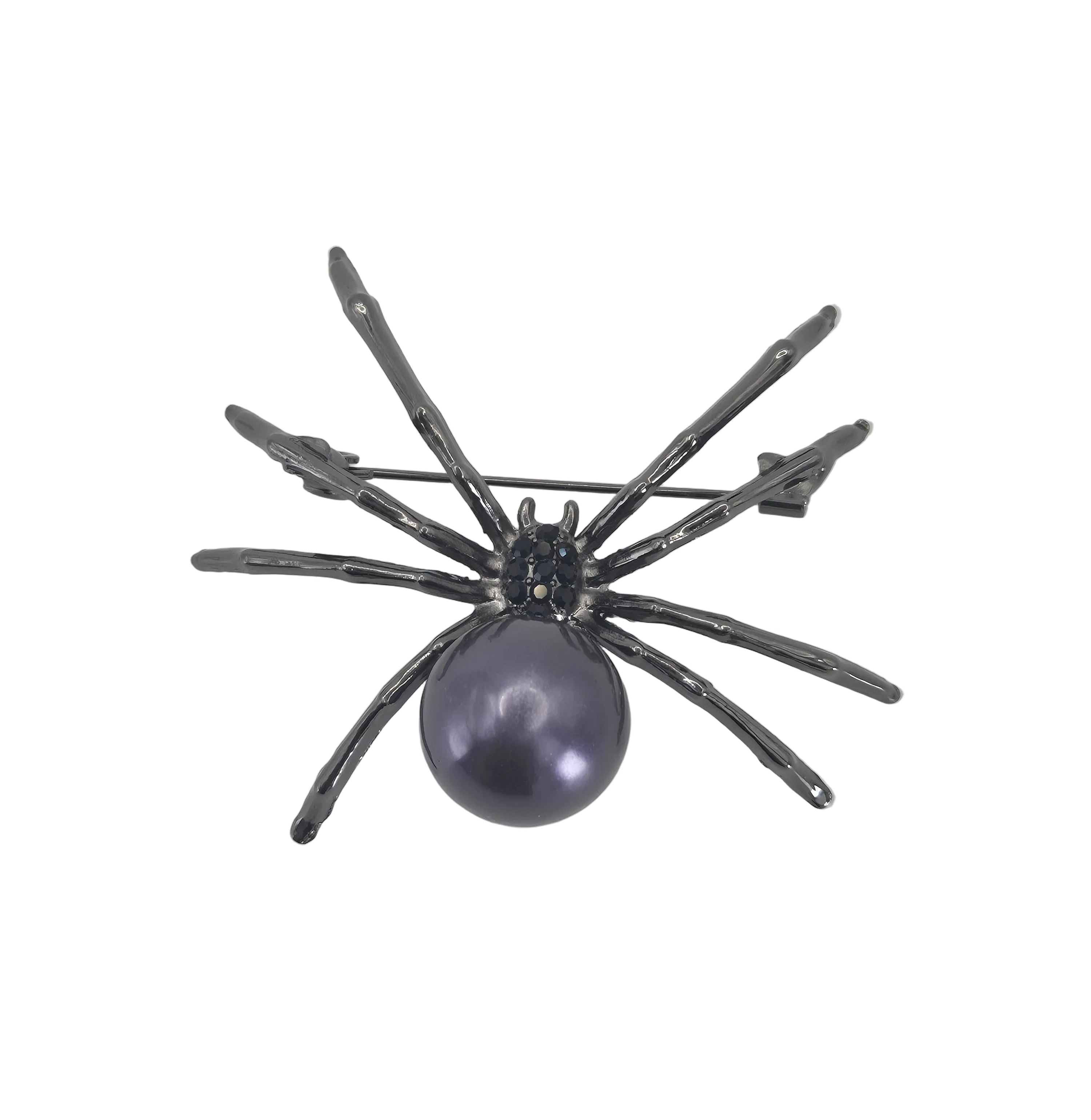 A spider-shaped brooch featuring a dark gray metallic body with a prominent oval purple pearl, photographed on a plain light gray background.
