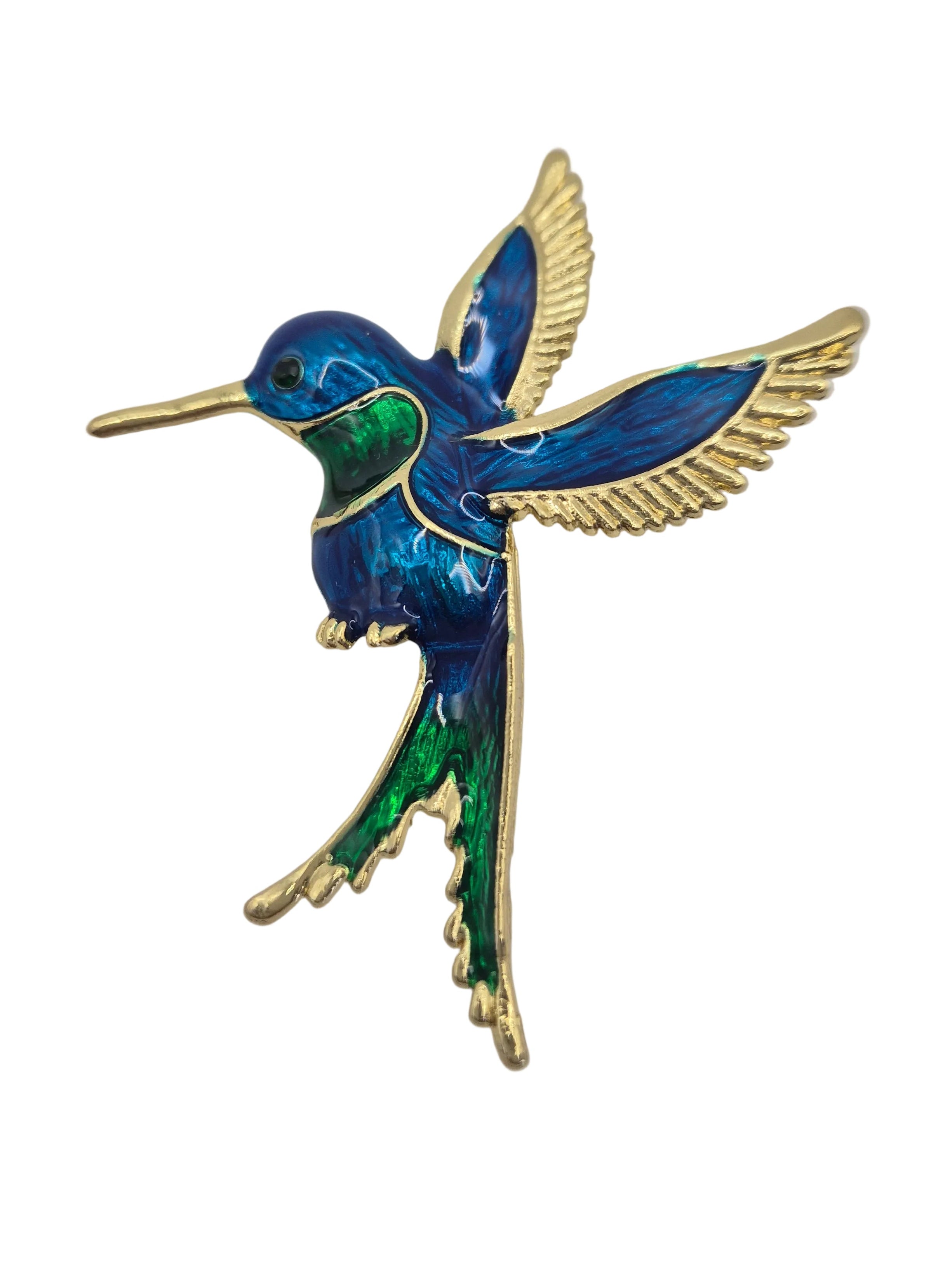 A hummingbird brooch featuring vibrant blue and green enamel with gold-tone metal outlines and wings, set against a plain white background.