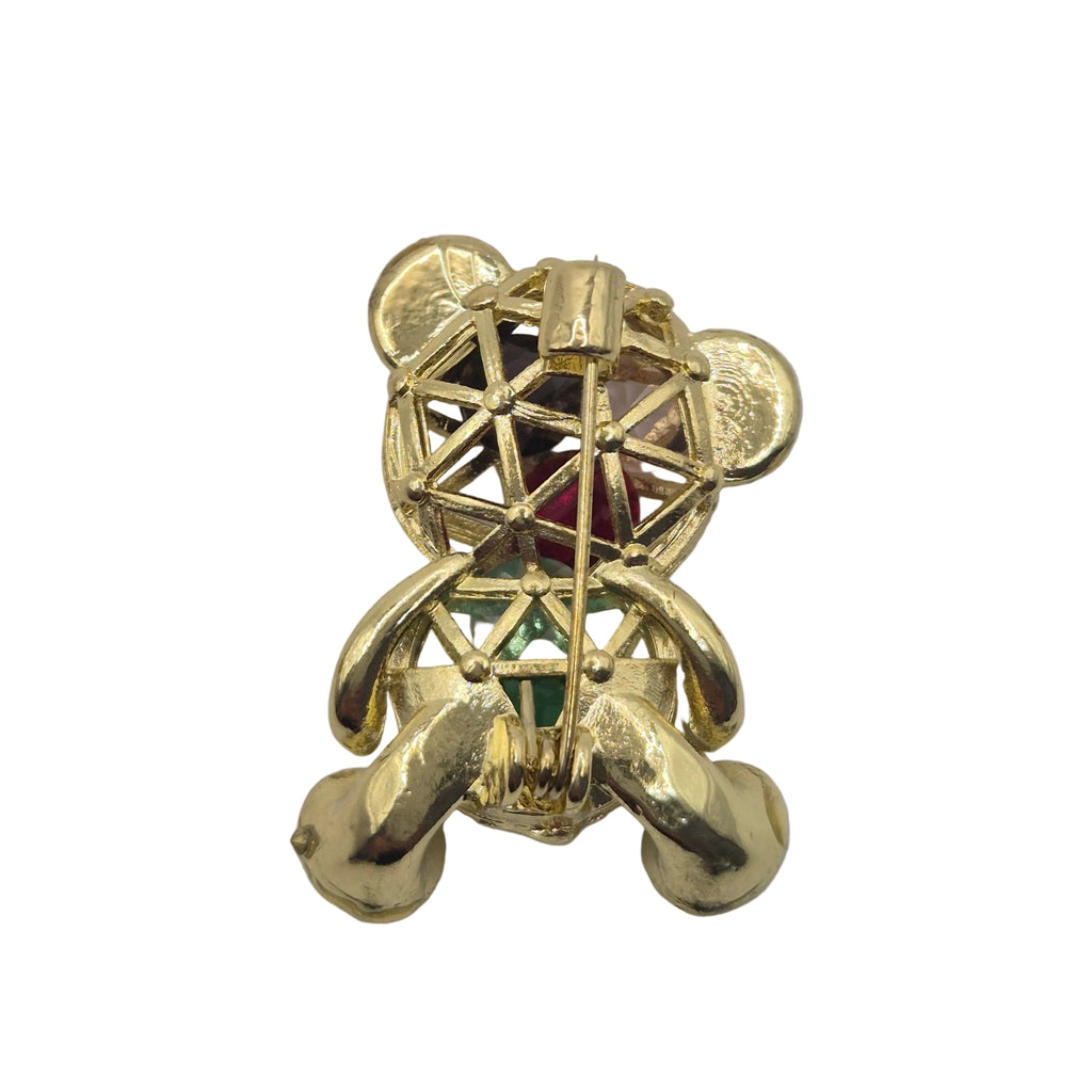 A gold-toned bear shaped brooch with colorful faceted gemstones, shown against a plain white background.