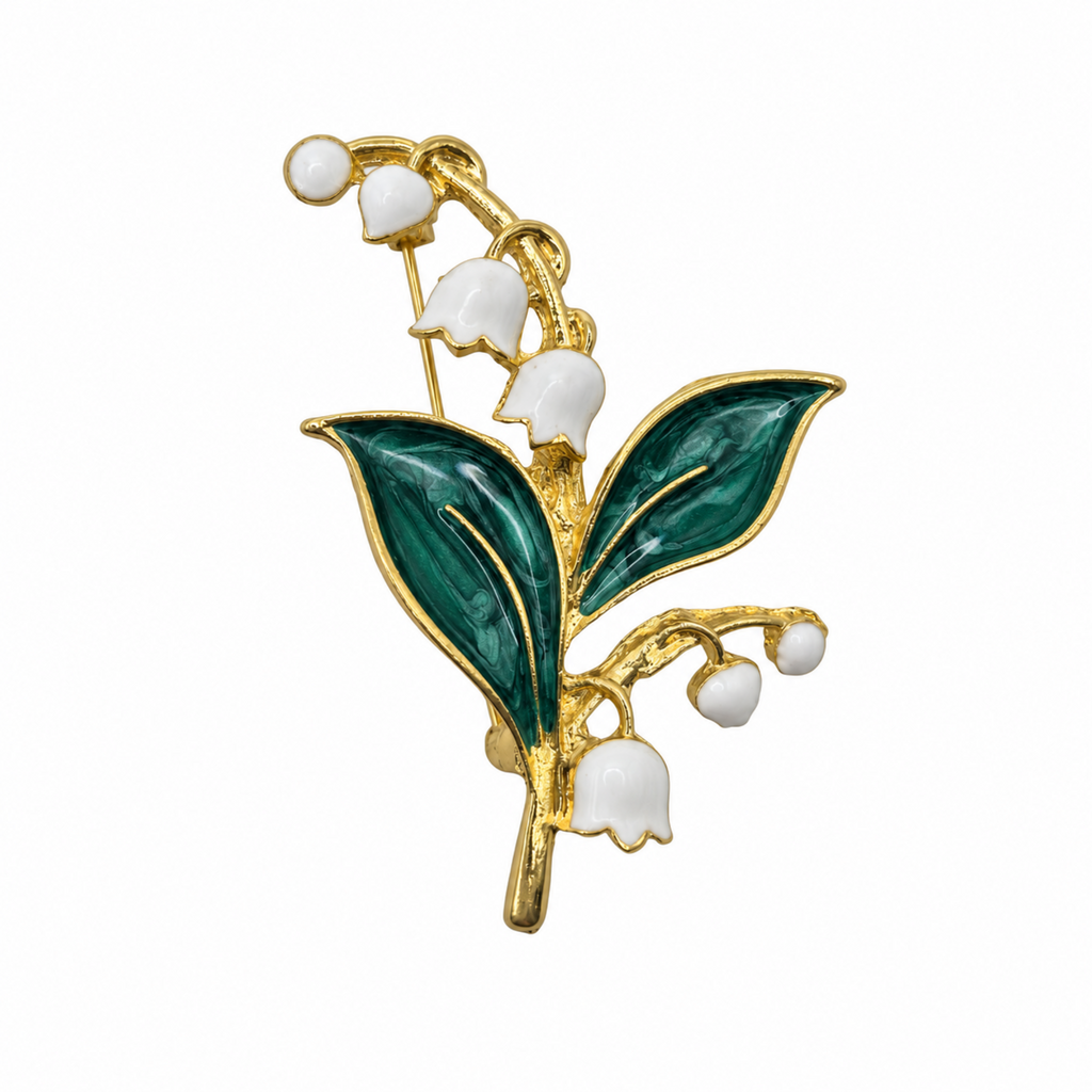 Gold lily of the valley flower brooch with green enamel leaves and white enamel bell-shaped flowers on a plain white background.