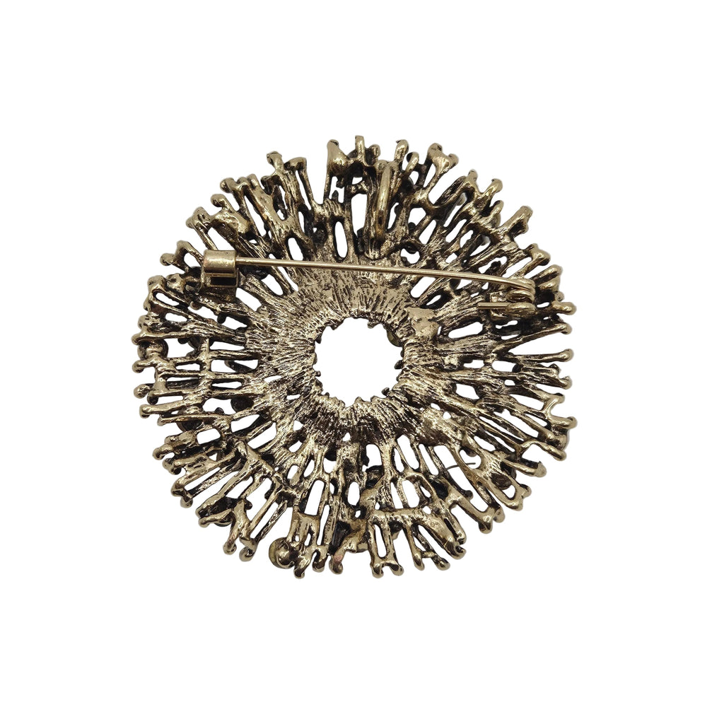 Reverse side of an antique gold tone metal firework brooch, displayed against a plain white background.