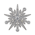A silver snowflake or star shaped brooch or pin embellished with clear crystals, shown on a plain white background.