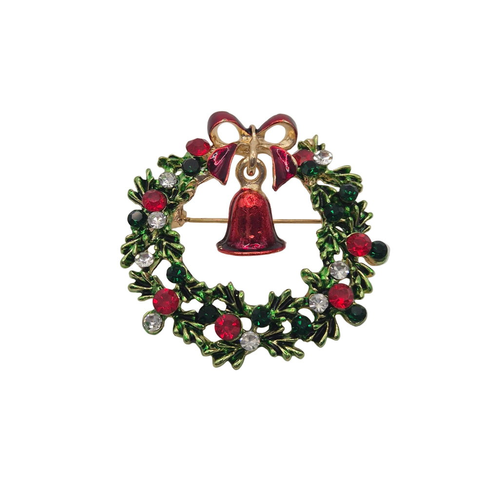 A Christmas wreath brooch with a gold-tone metal base, decorated with green holly leaves, red berries, clear rhinestones, and a central red bell with a red bow at the top.