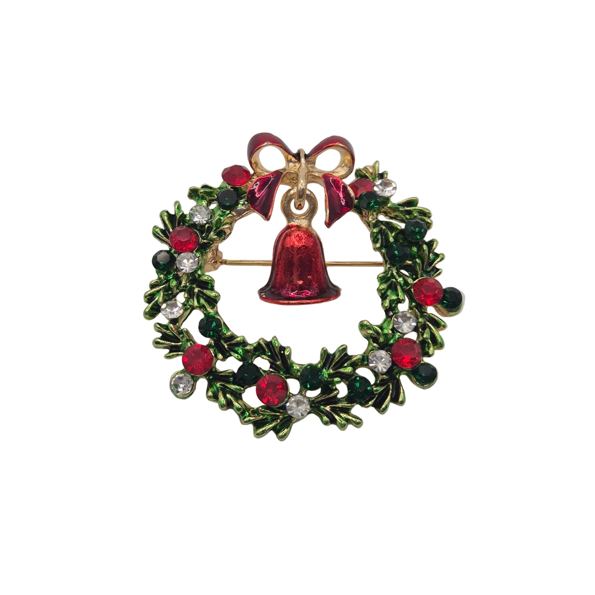 A Christmas wreath brooch with a gold-tone metal base, decorated with green holly leaves, red berries, clear rhinestones, and a central red bell with a red bow at the top.