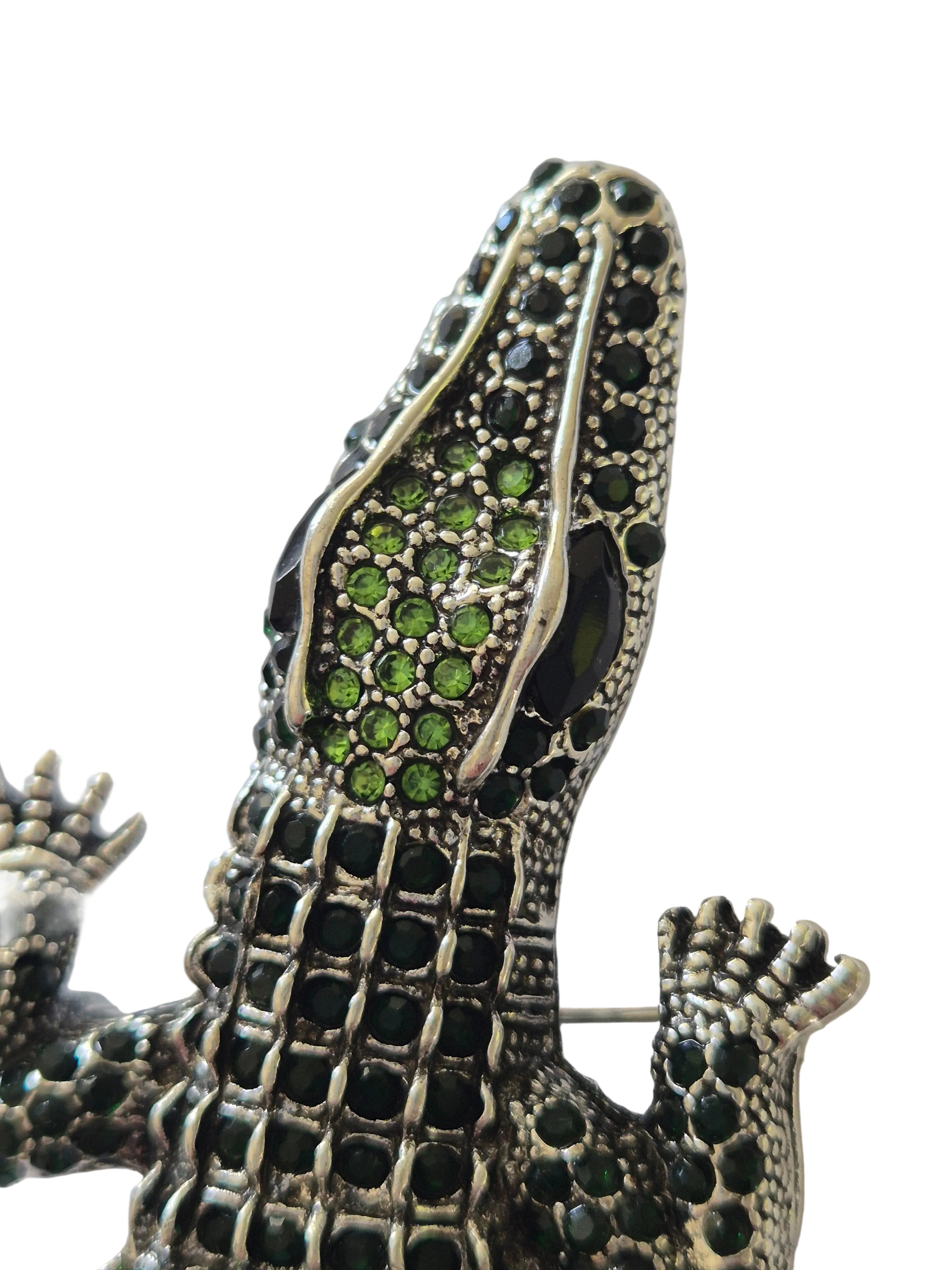 Decorative crocodile brooch with gemstone details on a white background