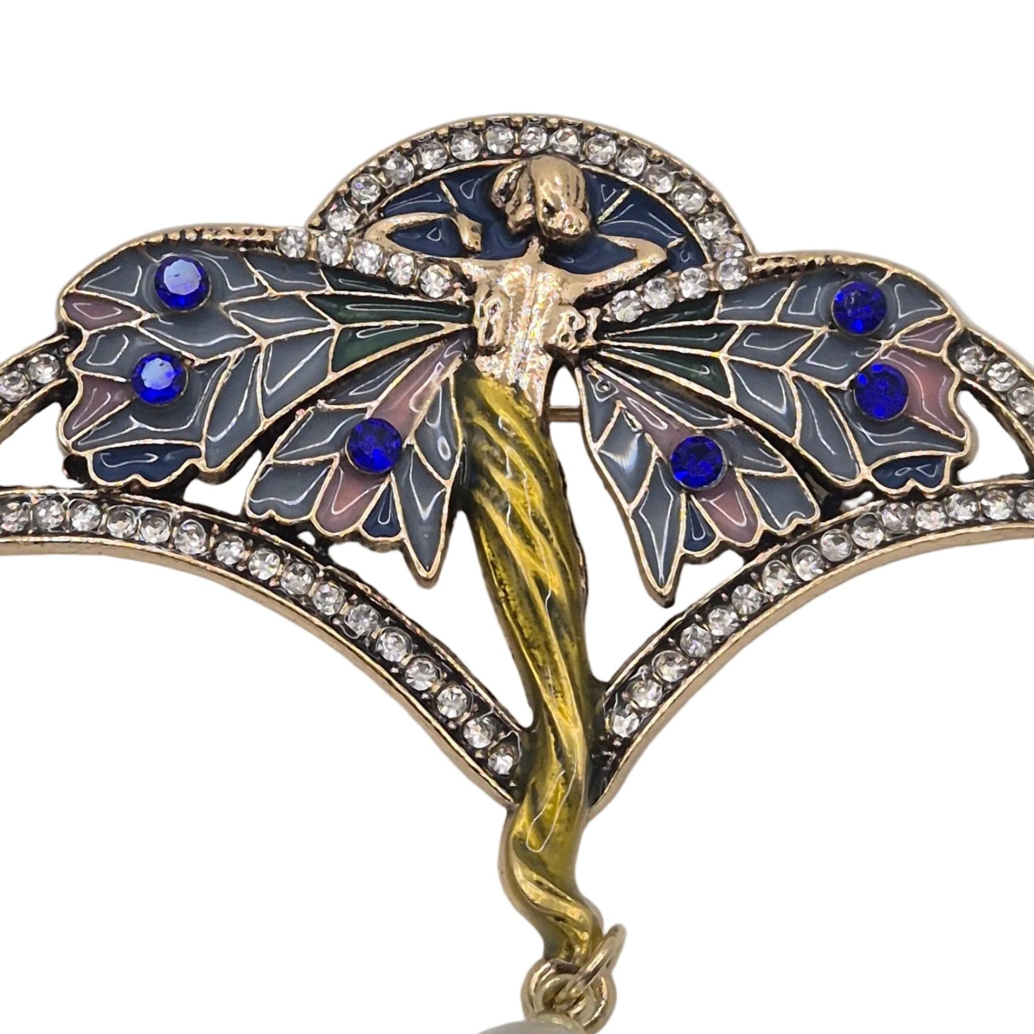 An Art Deco style brooch featuring a winged fairy figure with blue and gold enamel details, set with clear rhinestones and hanging from a white pearl drop, shown on a plain white background.