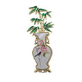 A decorative enamel pin shaped like a white porcelain vase with gold trim, pink flowers, a small bird, and green bamboo leaves on a white background.