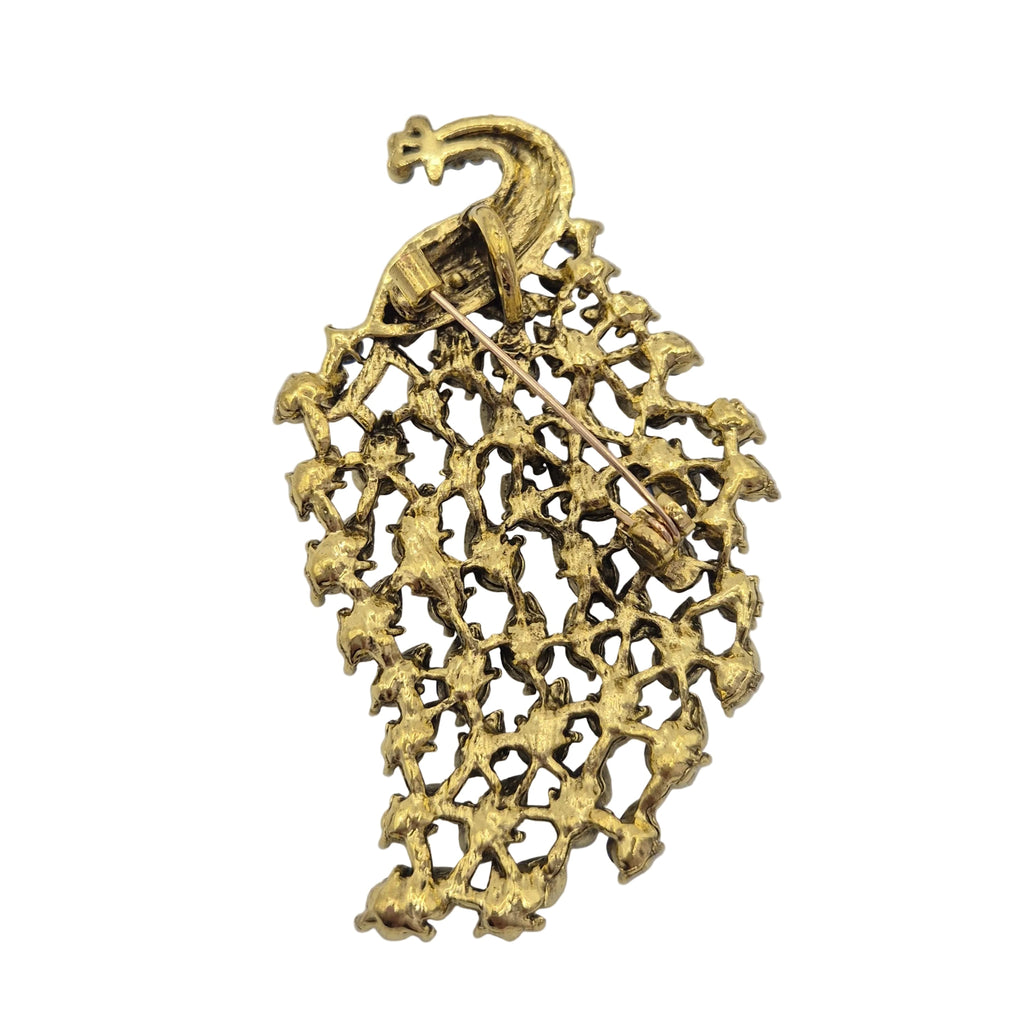 A vintage gold-tone brooch featuring a stylized peacock head at the top and an intricate, openwork lattice or floral pattern below, photographed on a plain white background.