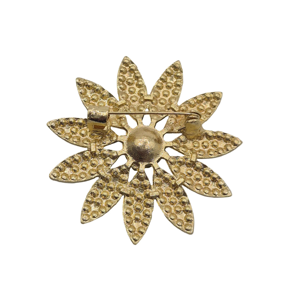A gold-tone metal flower-shaped brooch with textured, beaded petals and a central round detail, shown on a plain white background.