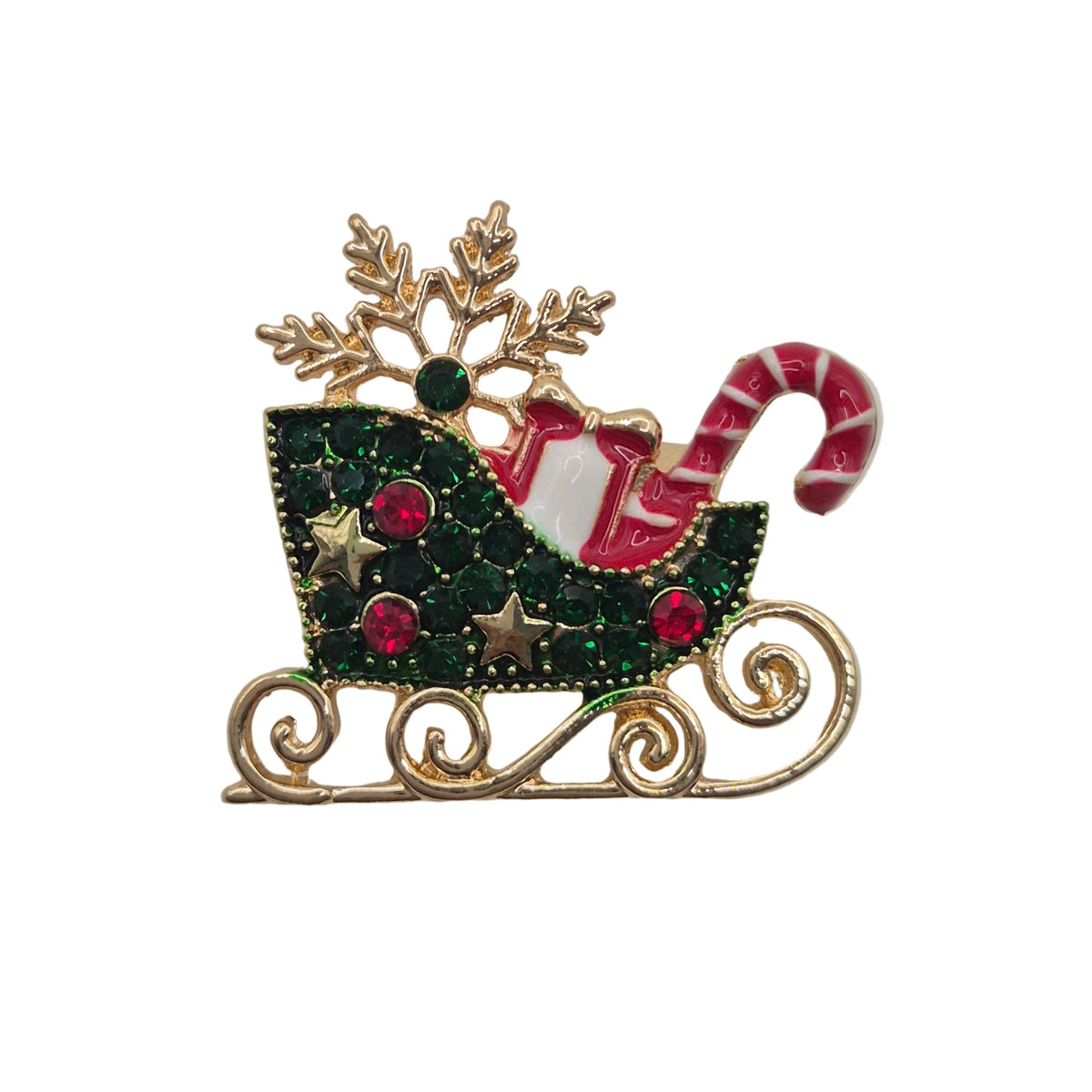 A Christmas-themed brooch featuring a gold-tone sleigh decorated with green rhinestones, red gem accents, a red-and-white striped candy cane, and a gold snowflake on a plain light background.