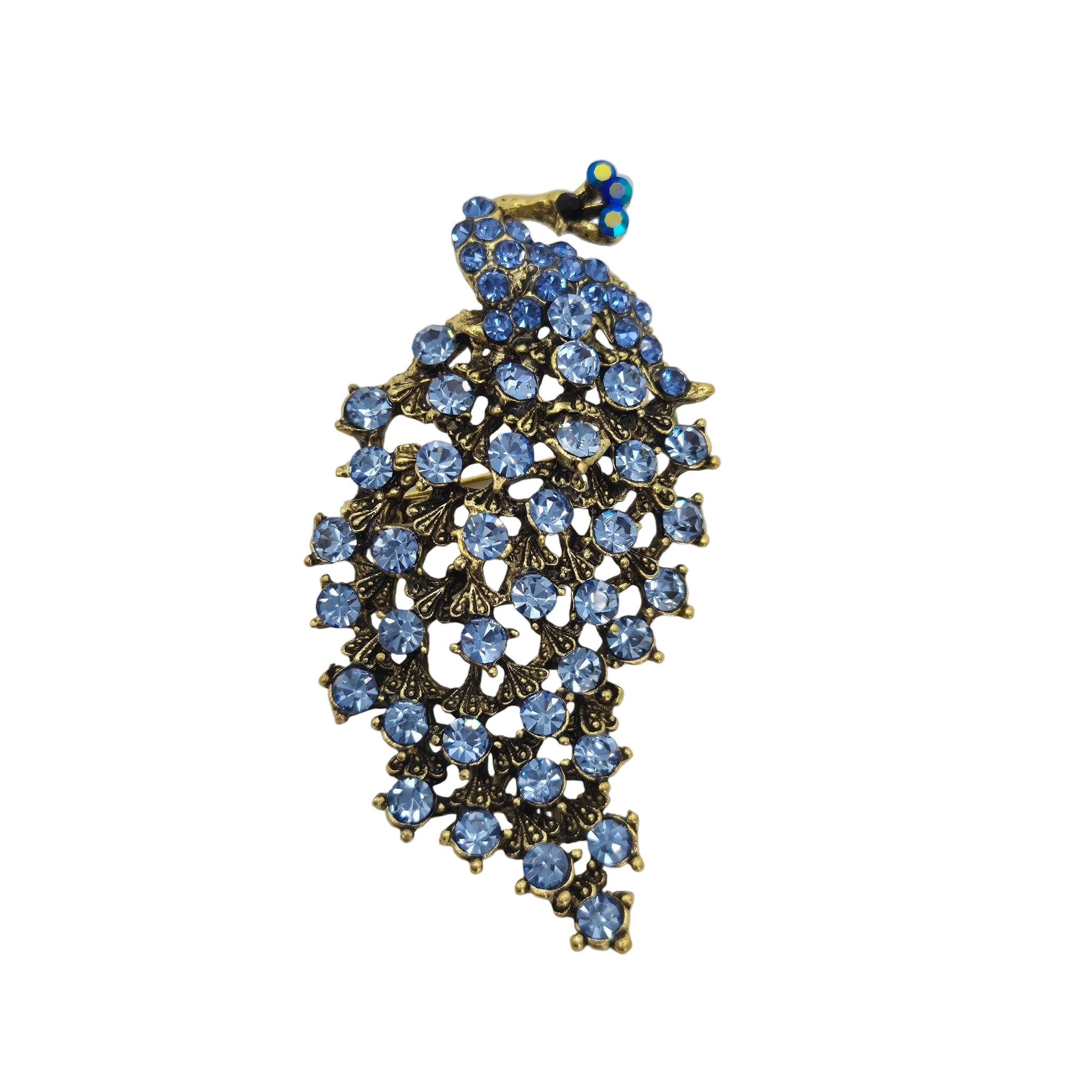 A vintage-style brooch featuring a peacock motif adorned with light blue rhinestones and gold-toned metal, set against a plain white background.