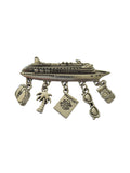 Silver charm brooch with various charms on a light gray background