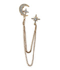 A gold-toned double-chain drop brooch featuring a crescent moon and star charm on one side and a starburst charm on the other, both adorned with clear rhinestones, shown on a plain white background.