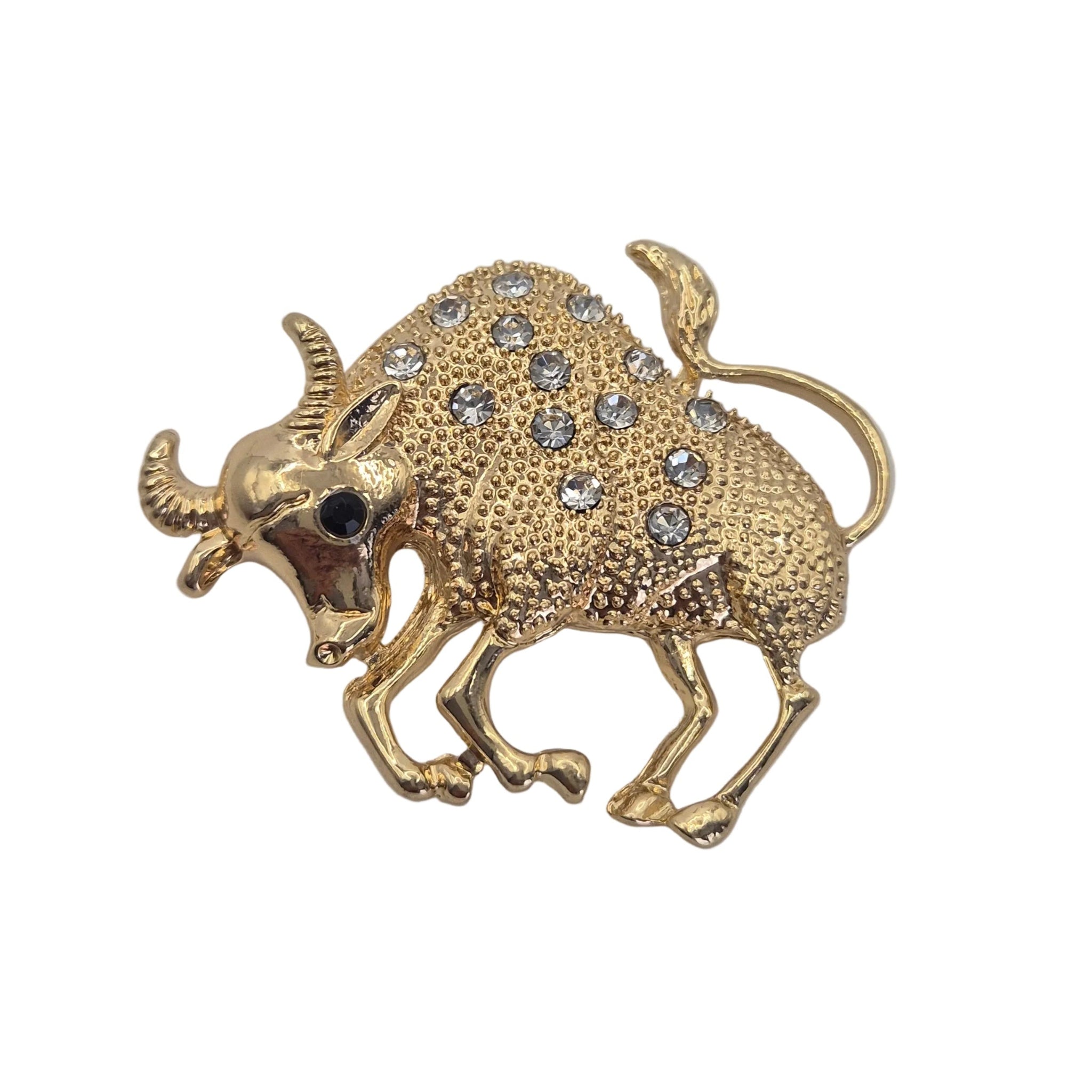 A gold Taurus bull zodiac sign shaped brooch decorated with small clear rhinestones, shown on a plain white background.