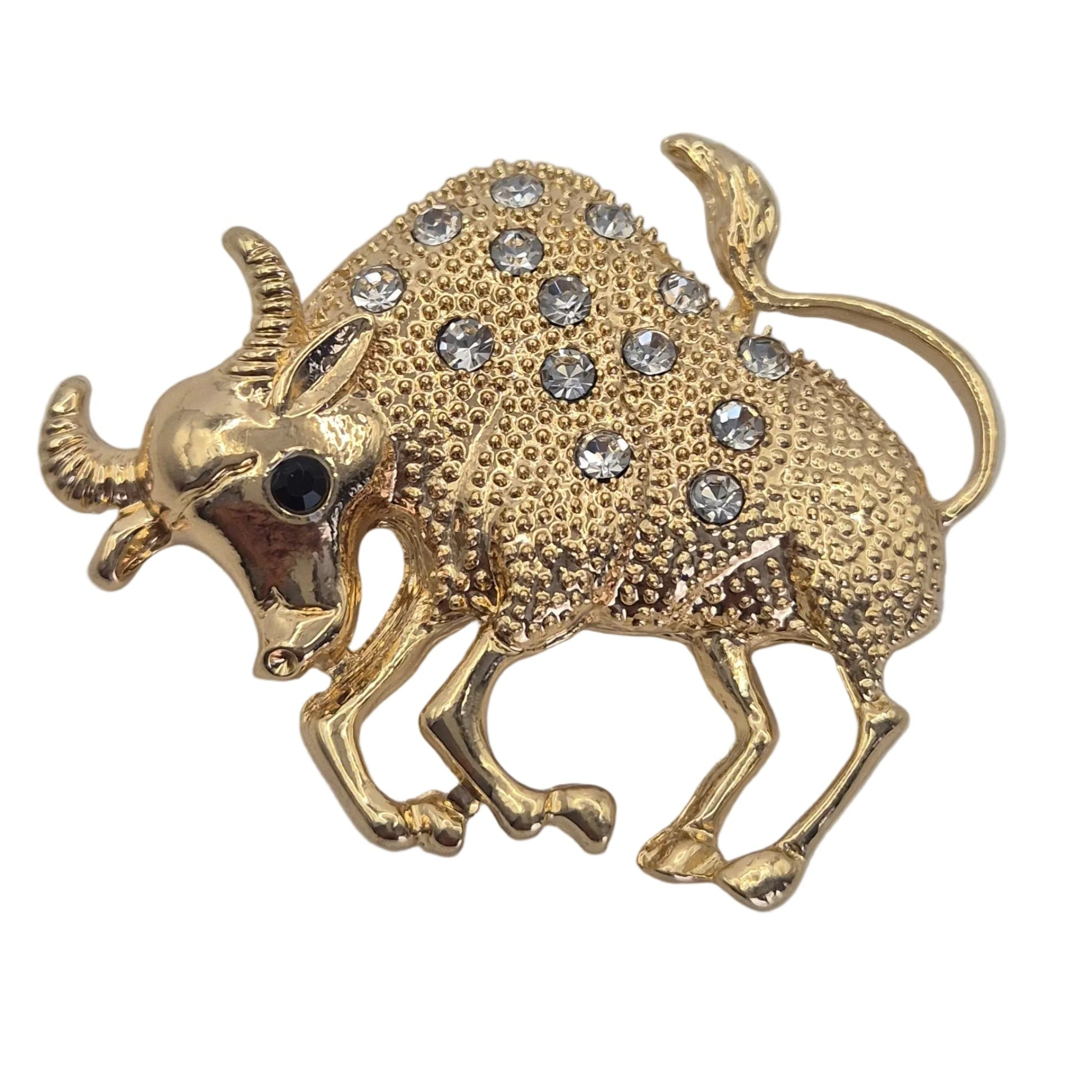 A gold bull-shaped brooch embellished with clear rhinestones on its back and shoulders, featuring a small black gemstone for the eye, set against a plain white background.