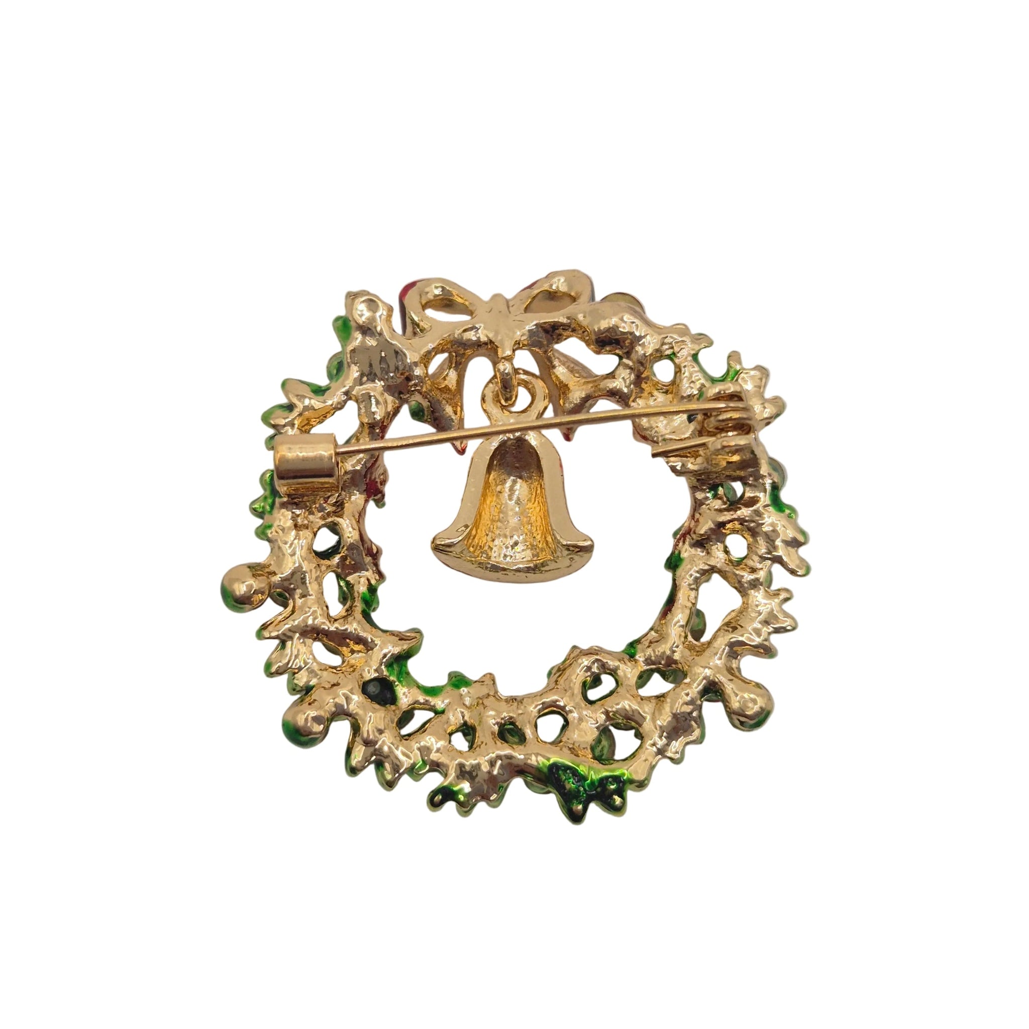 A vintage gold-tone Christmas wreath brooch with a small hanging bell and green enamel accents, shown on a plain white background.