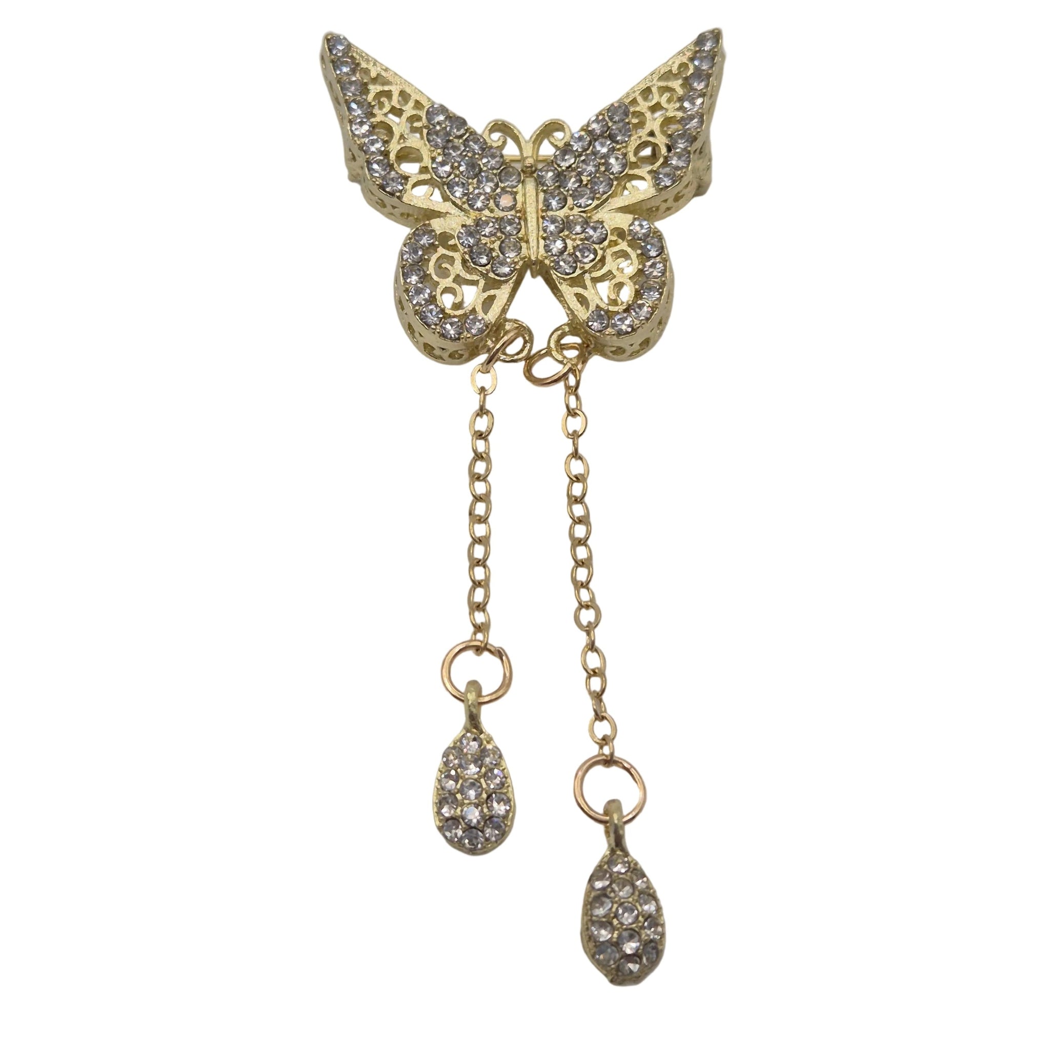 Gold butterfly brooch embellished with clear rhinestones, featuring two dangling chain drops with teardrop-shaped rhinestone charms, set against a plain light gray background.