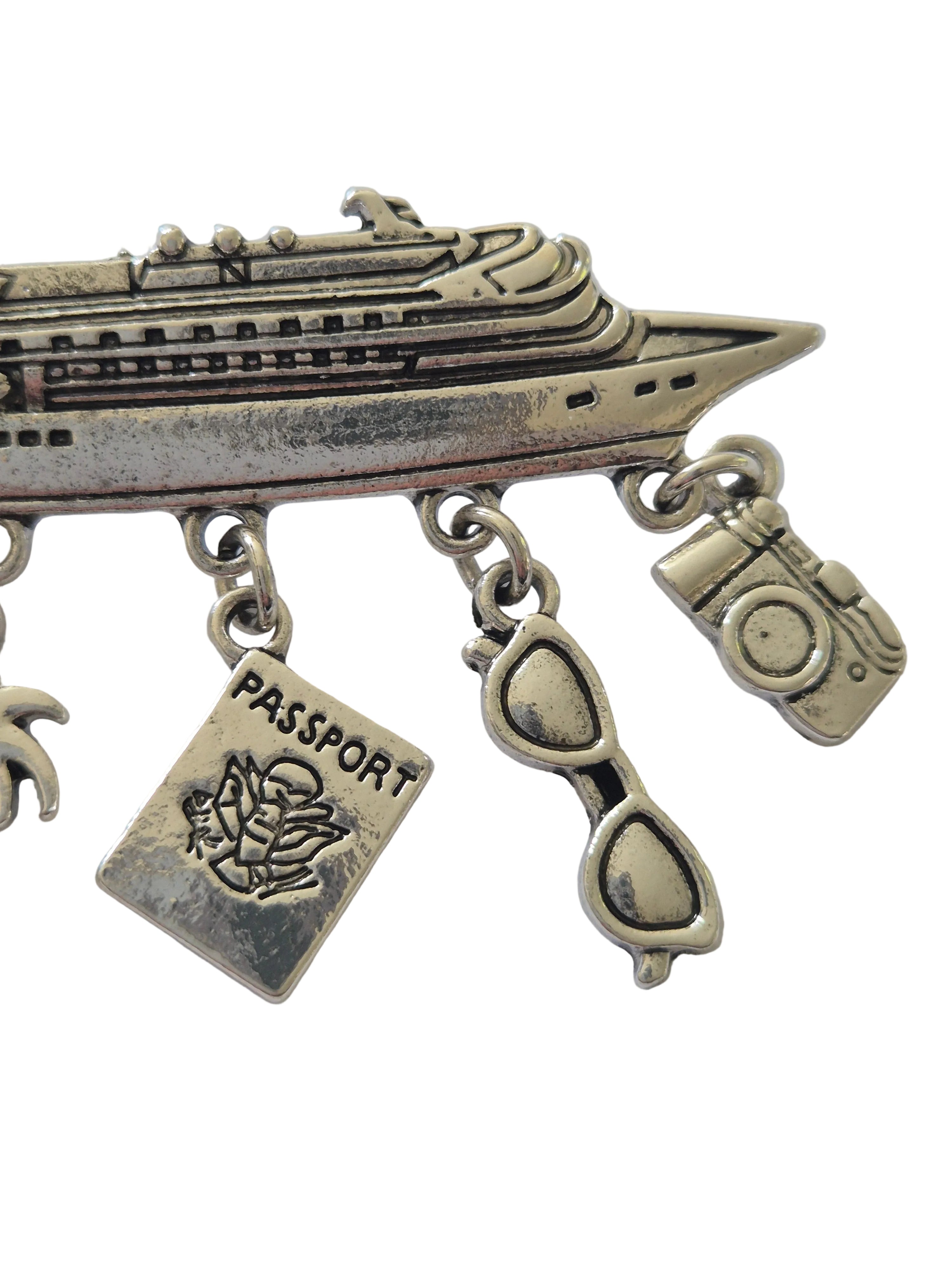 Silver charm brooch with various charms on a white background