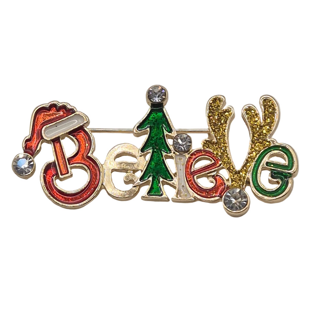 A festive enamel pin spelling out 'Believe' with holiday-themed lettering. The 'B' is shaped like a red Santa hat with a silver gem, the 'e' is gold glitter, the 'l' is red glitter, the 'e' is green glitter, the 'v' is a green Christmas tree, and the 'u' has gold glitter antlers.