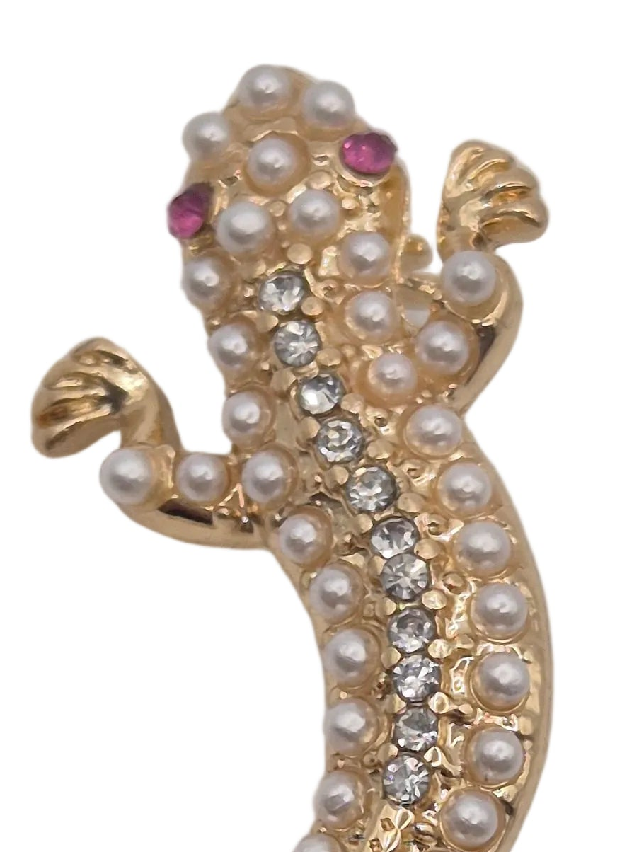 Gold lizard-shaped brooch embellished with white faux pearls, clear rhinestones, and pink gemstone eyes on a white background.