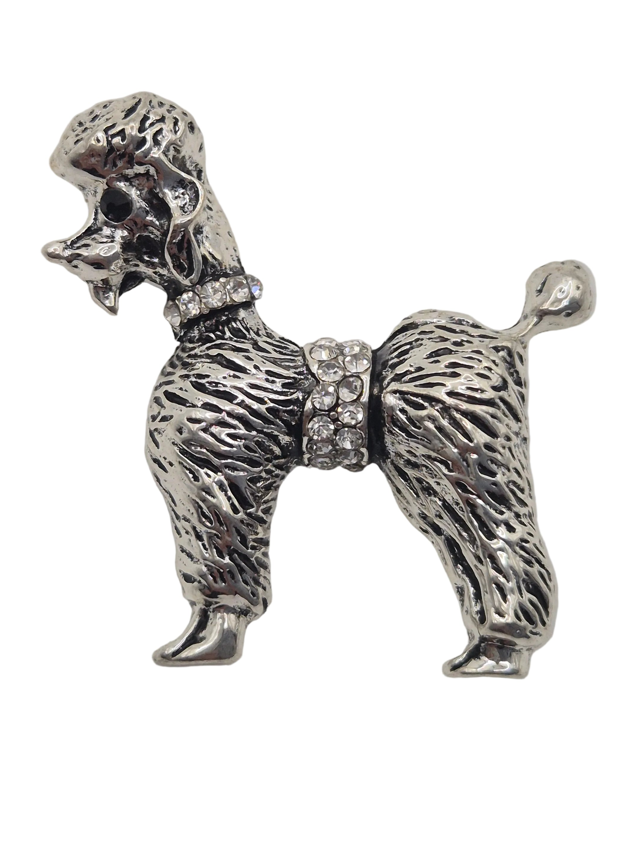 A silver-tone poodle-shaped brooch or pin with textured fur detailing and rhinestone accents on the collar and midsection, shown against a plain white background.
