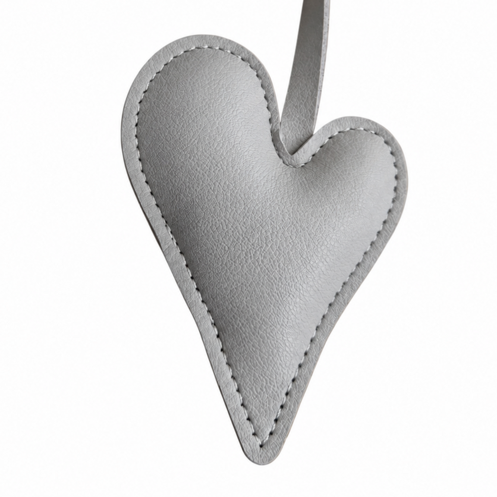 A light gray textured leather heart shaped bag charm with a matching curved strap, shown on a plain white background.