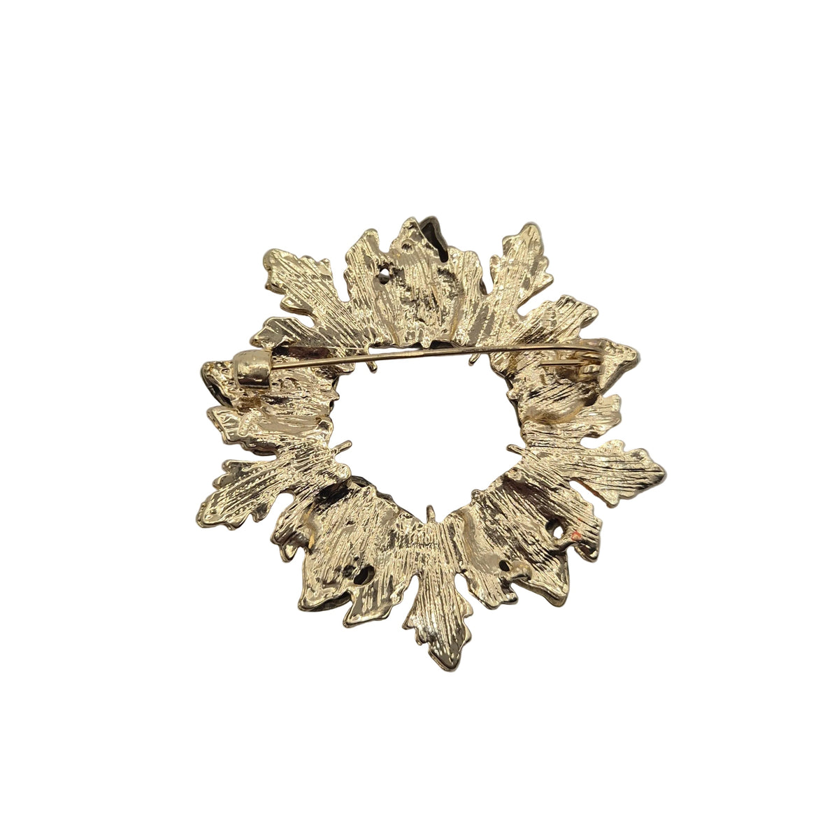 Reverse gold tone side of a autumn leaf wreath brooch showing the pin mechanism. Displayed against a plain white background.