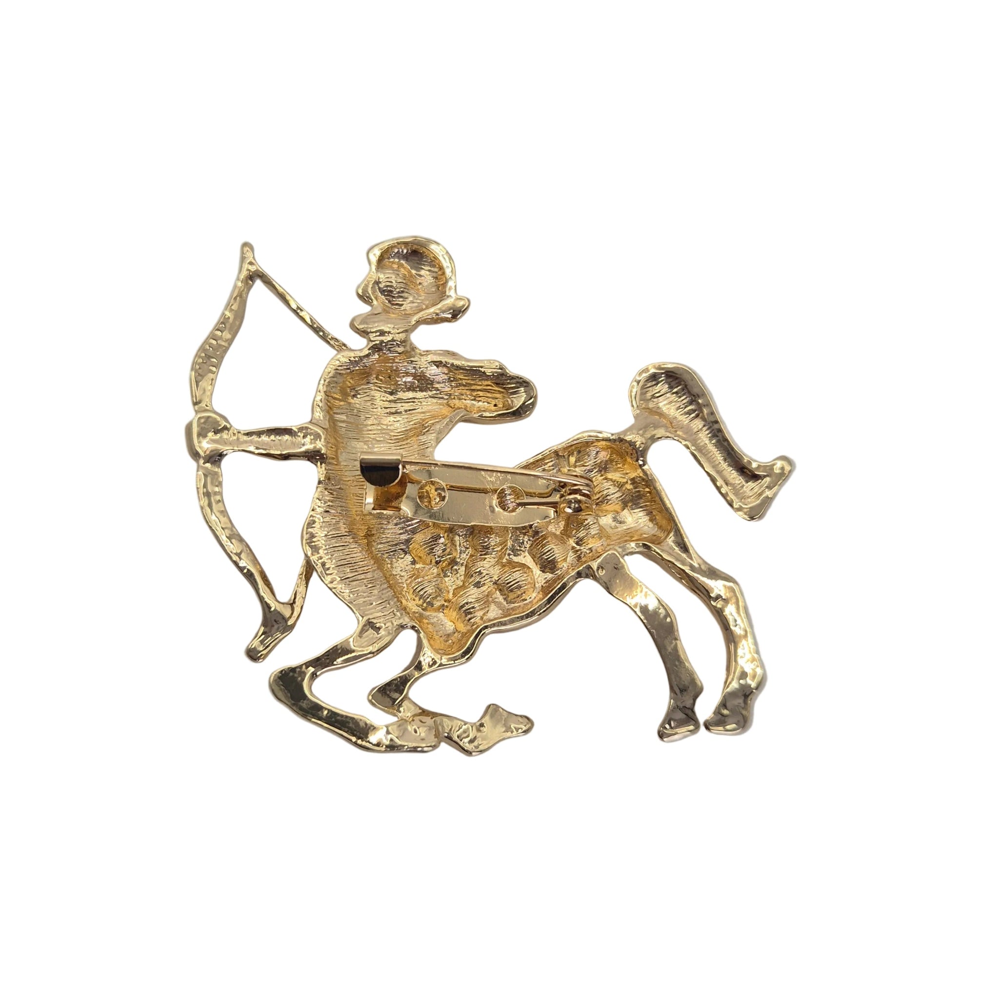 A gold-tone metal brooch depicting a Sagittarius zodiac sign, shown from the back to reveal the pin mechanism, on a plain white background.