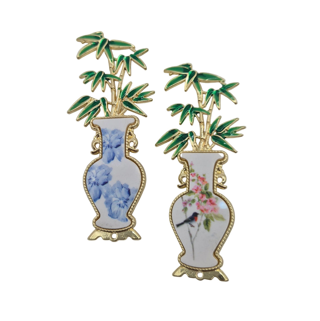 Two decorative enamel pins shaped like white porcelain vases with bamboo and floral designs, displayed on a plain white background.