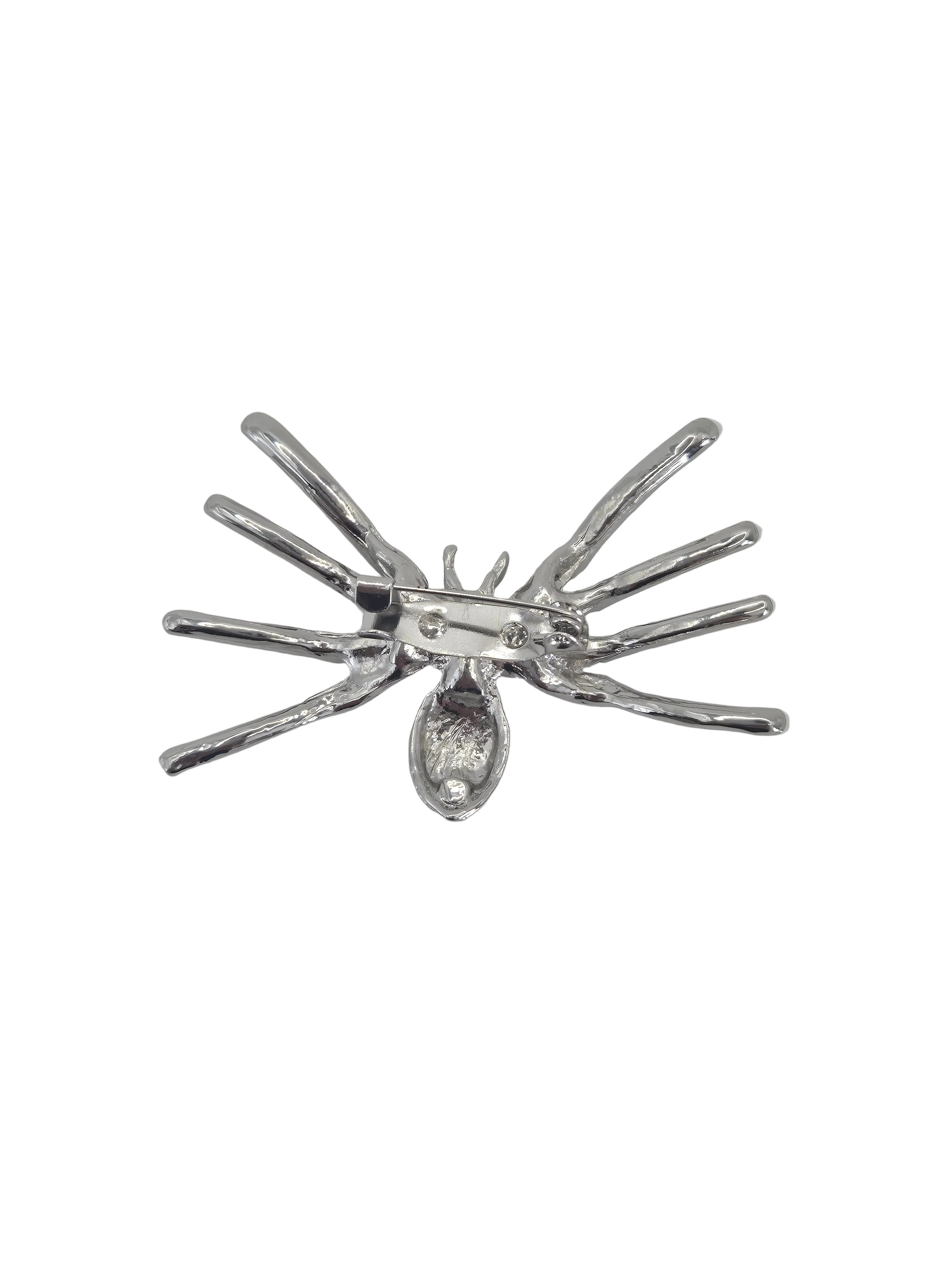 A silver spider brooch on reverse side set against a plain white background.