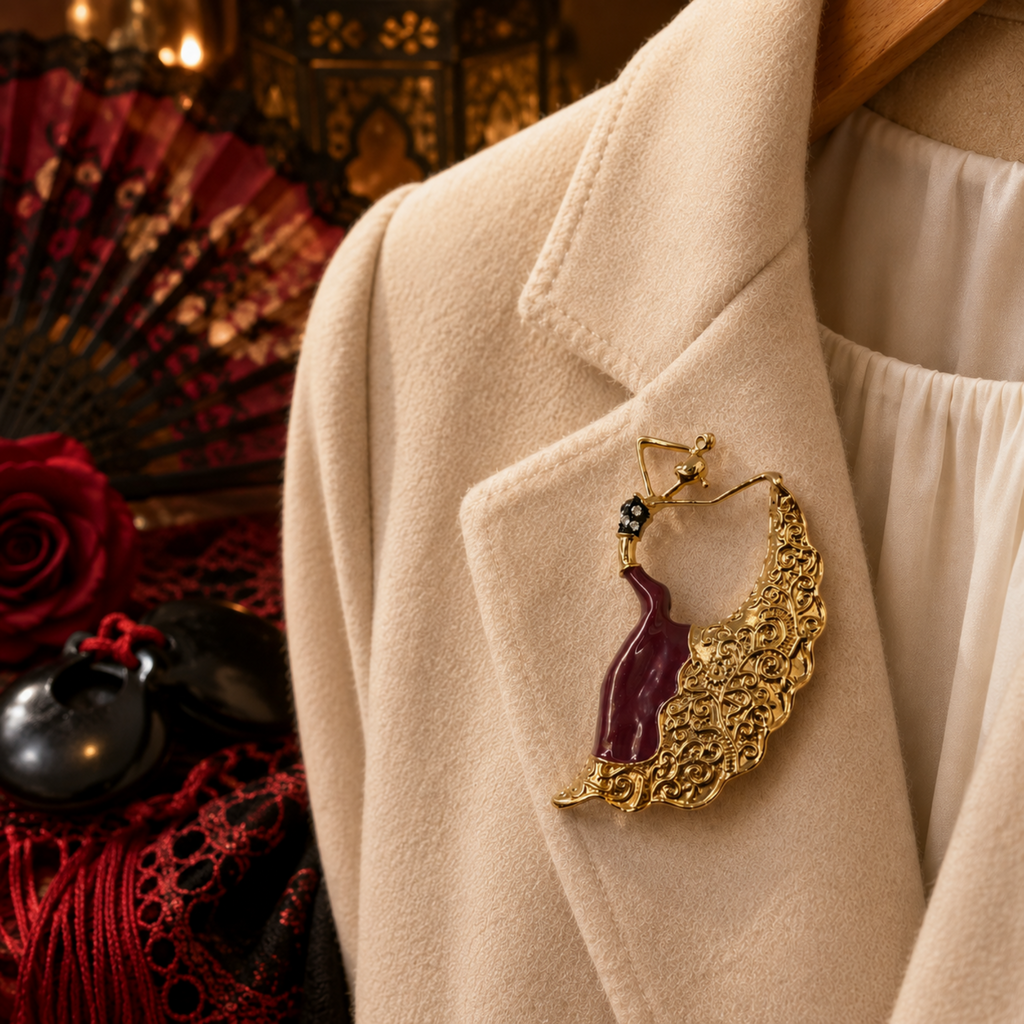 Gold-tone dancing woman brooch with burgundy enamel dress, ornate flowing skirt and sparkling rhinestone detail. Shown on lapel of cream jacket with red Spanish theme background.